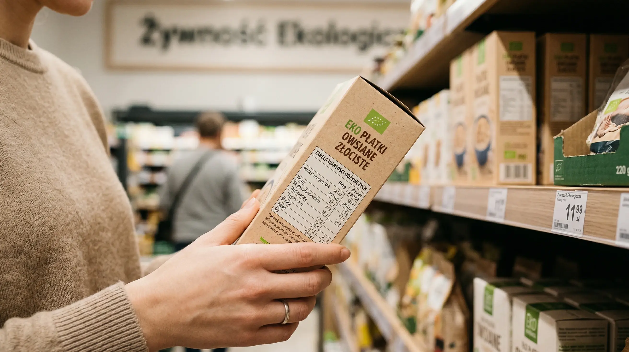 Dłoń trzymająca produkt spożywczy i czytająca etykietę w sklepie